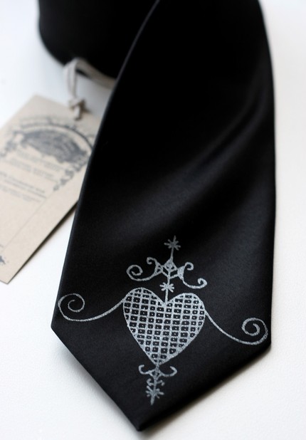 A black tie with a stylized and embellished heart screen-printed on the end