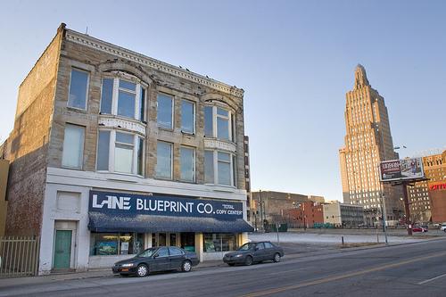 A late 19th-century 3-story cream brick building with a blue banner and awning reading LANE BLUEPRINT CO. TOTAL COPY CENTER, at 1520 Main Street in Kansas City, Missouri.