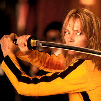 A still shot of Beatrix Kiddo “The Bride” in a yellow and black track suit, sweaty, with a Japanese sword, looking threateningly off image.