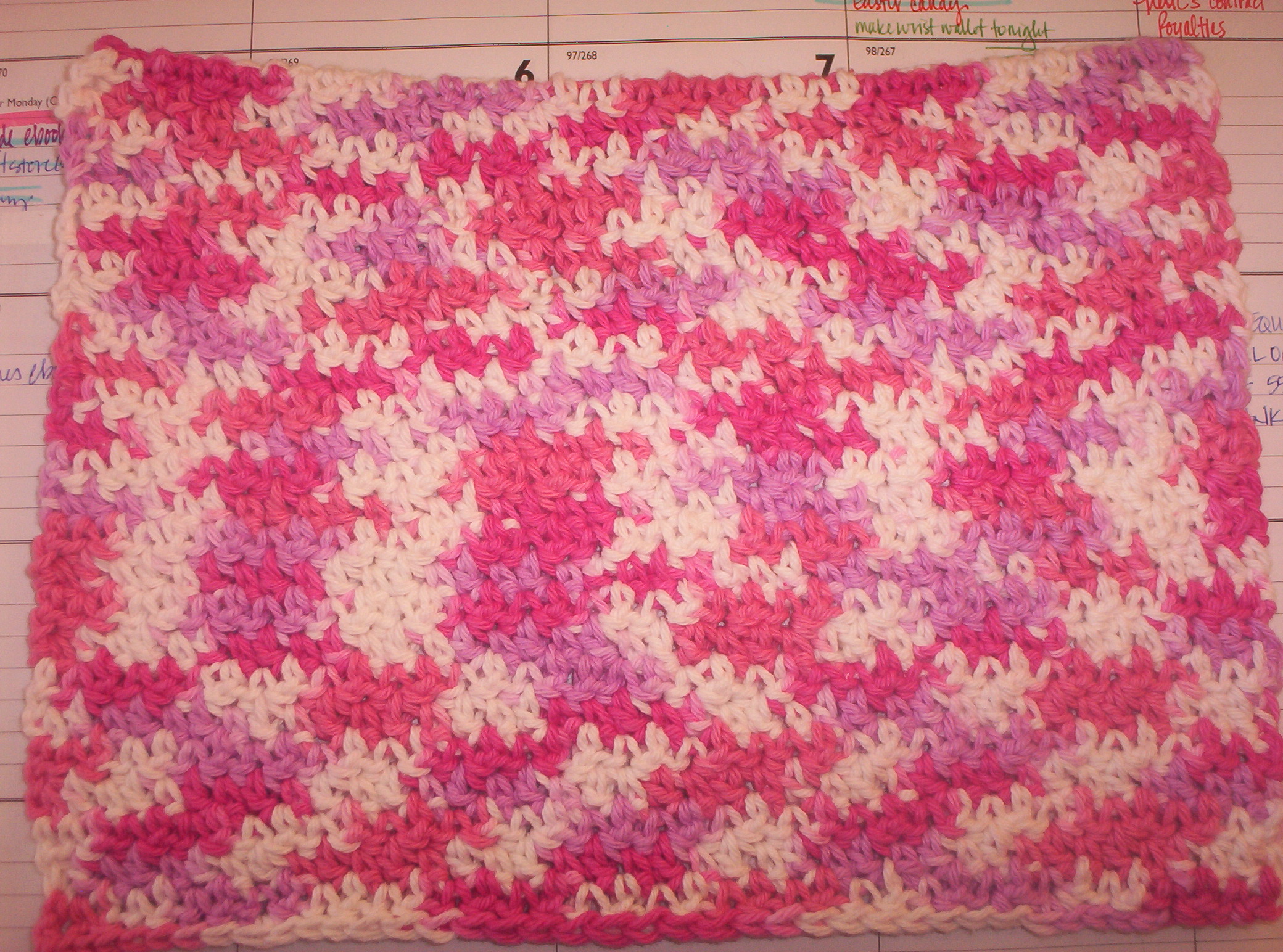A swatch of dishcloth stitch in Lily Sugar’n Cream “strawberry” variegated white, pink, dark pink cotton yarn.