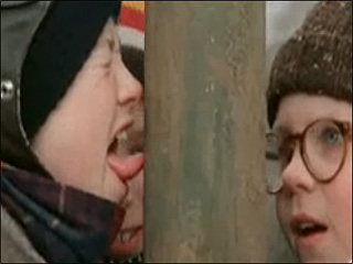 A still shot from A CHRISTMAS STORY of a young boy with his tongue stuck to a frozen metal pole, with another young boy looking on in amazement.