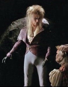 An image of David Bowie in medieval-ish clothes talking to a muppet, with his bulge on clear display through his tight pants.
