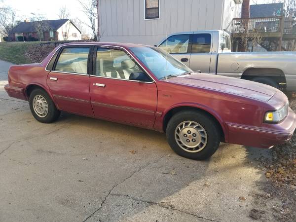 An image of a maroon 1996 Oldsmobile Cutlass Ciera with peeling clear-coat.