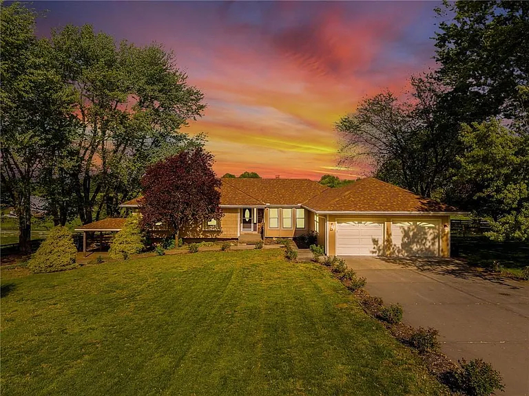 A ranch-style house with a big lawn and a two-car garage at sunset.